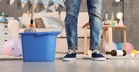 Man cleaning up after a party with a mop and bucket